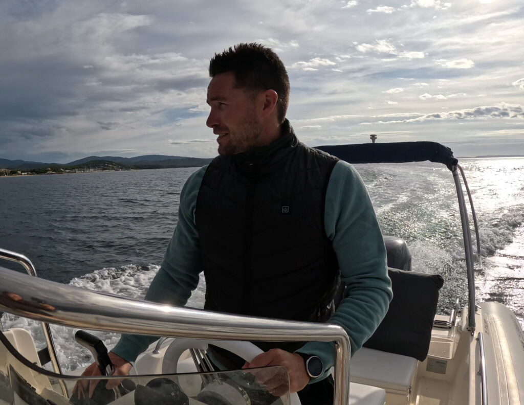 Veste chauffante sans manches E-KAUF portée à la barre d'un bateau, en mer